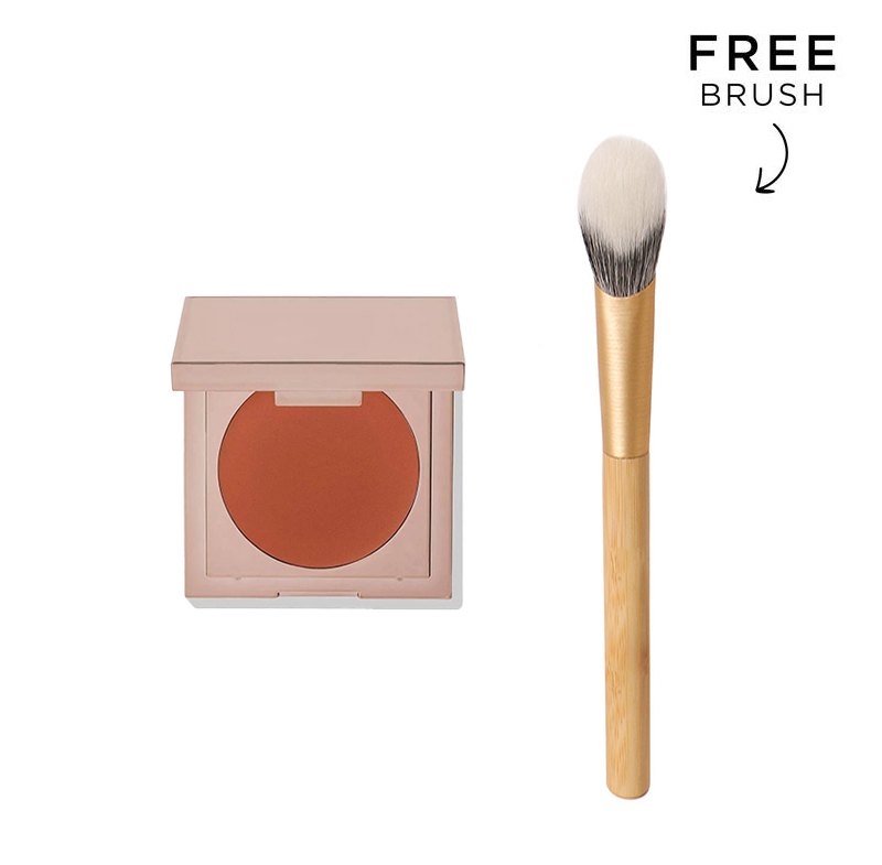 K-Beauty undereye corrector concealer in a rose gold compact next to a tapered makeup brush for dark circle coverage.