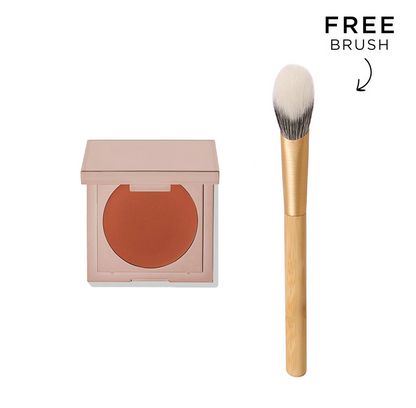 K-Beauty undereye corrector concealer in a rose gold compact next to a tapered makeup brush for dark circle coverage.