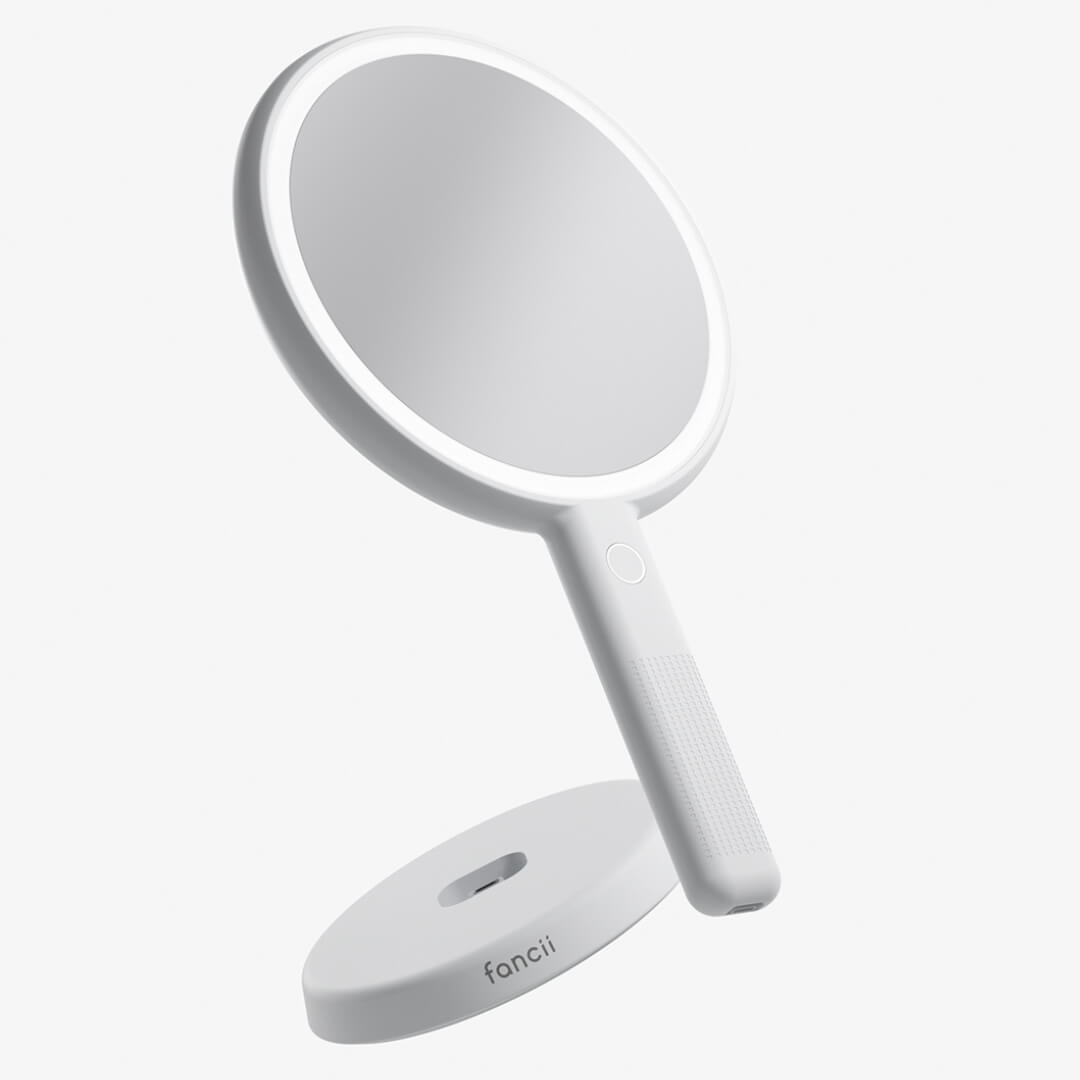 White Cami LED lighted handheld makeup mirror with 1x/5x magnification and a fanii brand vanity charging base.