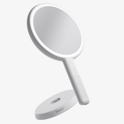 White Cami LED lighted handheld makeup mirror with 1x/5x magnification and a fanii brand vanity charging base.