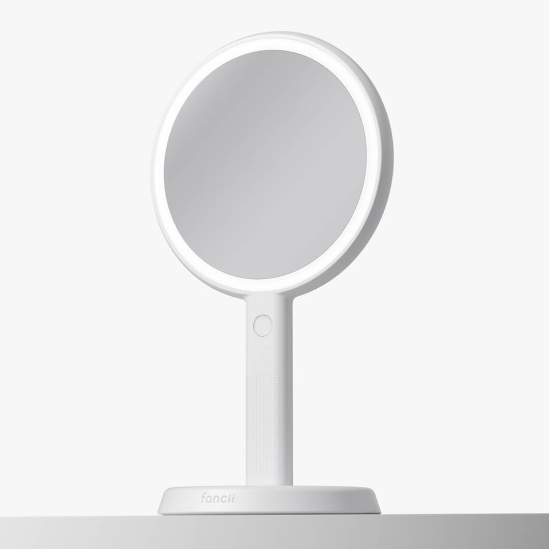 White Cami lighted handheld makeup mirror with 1x/5x magnification and 52 LED lights shown on its vanity stand.