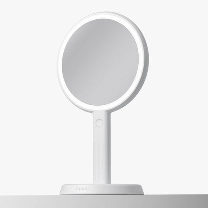 White Cami lighted handheld makeup mirror with 1x/5x magnification and 52 LED lights shown on its vanity stand.