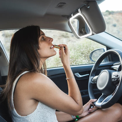 Woman applying lipstick using the Juni 2 LED lighted car visor mirror, a portable vanity for travel makeup touchups.