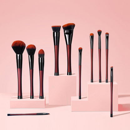 Aria Pro 12-piece makeup brush set in Merlot red on pink display pedestals. Professional vegan brushes with soft bristles.