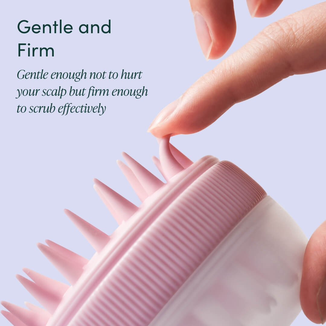 Charlotte pink silicone scalp massager with soft flexible bristles being tested for firmness for hair exfoliation.