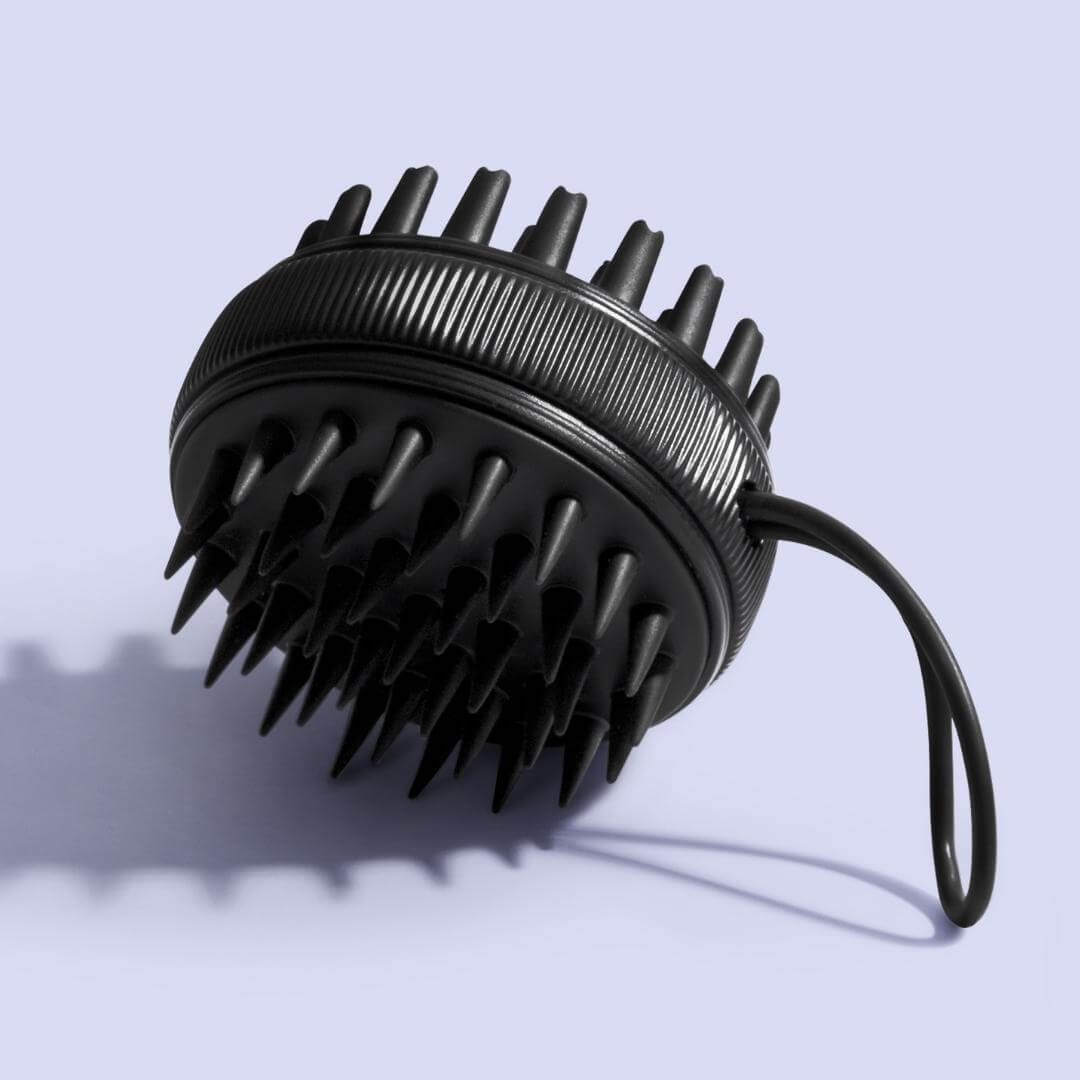 Black Charlotte silicone scalp massager brush for hair growth and exfoliation, featuring a soft-bristle head and hand strap.