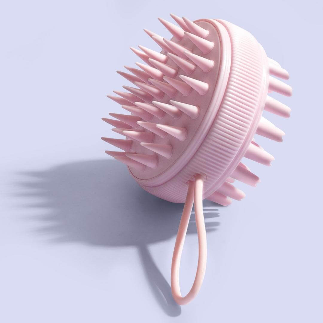 Pink Charlotte silicone scalp massager brush for hair growth and exfoliation, featured on a lavender background.
