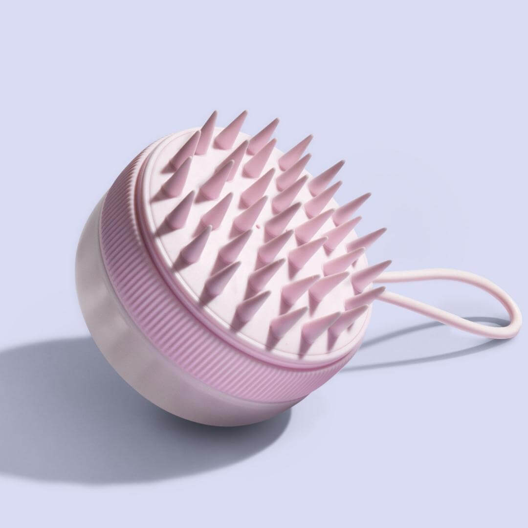 Pink Charlotte silicone scalp massager brush with exfoliating bristles for hair growth, shown on a light purple background.