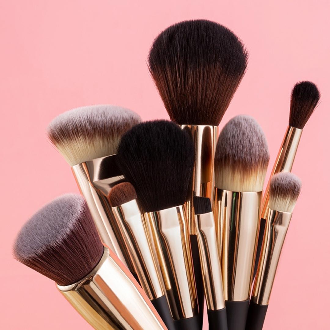 Aria Pro 12-piece makeup brush set with soft synthetic bristles and gold ferrules against a pink background.