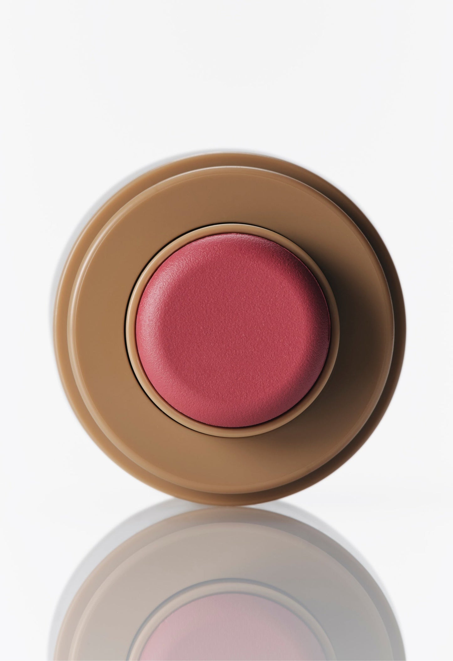 Pocket Blush in Teacup: A glowy pink cream blush in a round, tan portable tube against a white background.